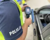 Policjant mierzy prędkość samochodu radarem.
