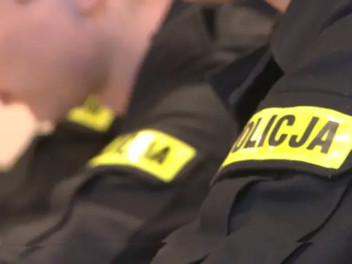 Zbliżenie na rękawy mundurów policyjnych z żółtymi naszywkami "POLICJA".