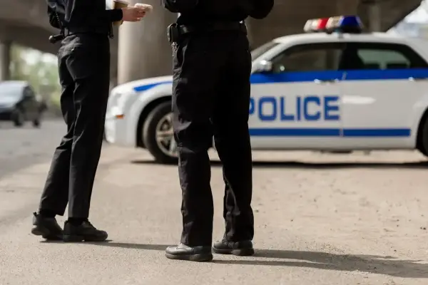 Dwóch policjantów stoi obok radiowozu.