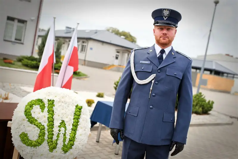 Mężczyzna w mundurze galowym SW, biało-zielony wieniec z napisem SW, polskie flagi.